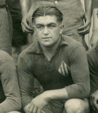 Photographie noir et blanc : c'est un portait d'un homme en maillot de sport qui regarde devant lui.