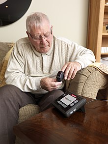 Older man puts a small electronic device on his finger tip at home