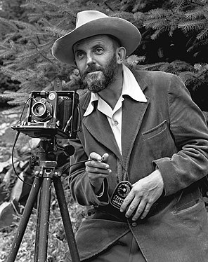 Nature photographer Ansel Adams. The camera is probably a Zeiss Ikon Universal Juwel. (created by J. Malcolm Greany and nominated by Pine)