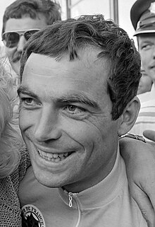 Photographie en noir et blanc de la tête d'un homme souriant.