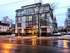 Photograph of a large, multi-storey, and rather blocky office building with a leafless tree out front