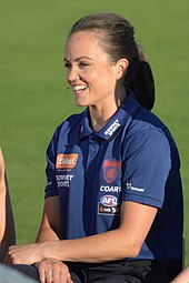 Pearce sitting at a desk wearing a Melbourne polo shirt