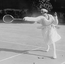 Lenglen hitting a forehand near the baseline in the doubles alley