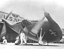 Image includes pilot Boone T. Guyton below the entrance trap door of the V-173. Image taken at Floyd Bennett Naval Air Station in New York.