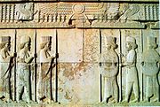 Stone-carved wall depicting Persians and Medes of the Achaemenid army under the Faravahar at the Apadana Hall in the city of Persepolis