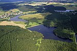 An aerial view showing several dammed lakes within a forested and urban landscape