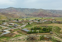 An image of the village taken from a high elevation. Multiple buildings are located off of a central road. Mir Gholam Hashemi Castle can be seen in the top right corner of the village.