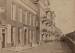 Woningen aan westzijde van de Hereweg naast het oorspronkelijke Herewegviaduct rond 1890. In de jaren 1930 werd de straat door de uitbreiding van het viaduct met een overkraging sterk versmald. Een aantal woningen werd daarvoor gesloopt. Van de oorspronkelijke bebouwing resteert alleen het zuidelijke en middendeel van het pand met de balkons.