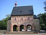 A stand-alone gatehouse surrounded by many trees.