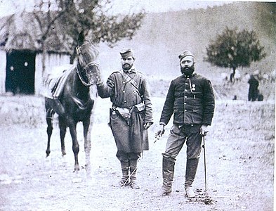 Српски војници и официри 1876., шајкача и чакшири су плаве боје, а блуза тамно смеђе.