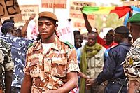 Un soldado de la guardia nacional de Malí, caminando entre los manifestantes, en el Aeropuerto Internacional de Bamako-Sénou.