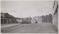 Het voorplein van het Weesperpoortstation, met links het stationsgebouw en rechts het tramstation en een motortram van de Gooische Tram; circa 1936.