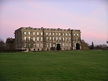 Au milieu d'une pelouse, façade d'un vaste bâtiment de trois étages sur rez-de-chaussée surélevé