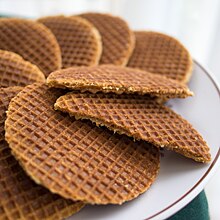 Thin, dark, round waffles; one cut in half shows a thin, internal layer of filling