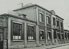 Carte postale en noir et blanc représentant un bâtiment administratif à la façade symétrique et surplombé en son centre d'un étage.