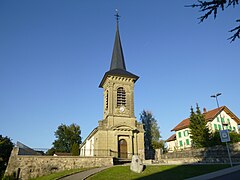 Zu sehen ist die Kirche von Arconciel in der Vorderansicht. Der Turm ist breit, das Kirchenschiff dazu vergleichsweise schmal.