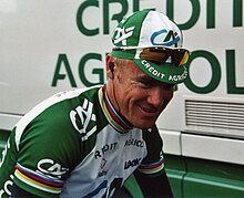 Photographie en gros plan d'un cycliste portant une casquette et un maillot vert et blanc.