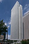 Ground-level view of a white, rectangular, window-dotted high-rise; one side is vertically bisected