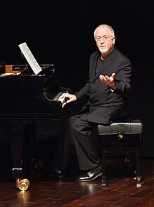 Un homme assit devant un piano.