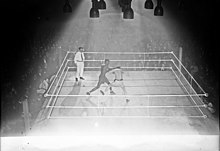 Photographie en noir et blanc prise de haut d'un combat de boxe.