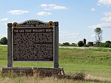 a wooden commemorative board in a field