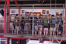 people listening to a presentation from behind a fence