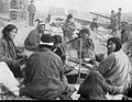 Group of Kets around a campfire. The people in the background wearing fur hats are Russians.[citation needed]