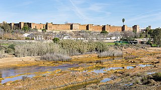 La muralla de Niebla vista desde la orilla opuesta del río Tinto