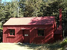 A bright red hiking shelter in a forested enviroment