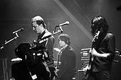 Black-and-white photograph of Queens of the Stone Age performing live in 2007.