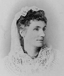 Black and white image of dark-haired woman with white veil over the back of her head