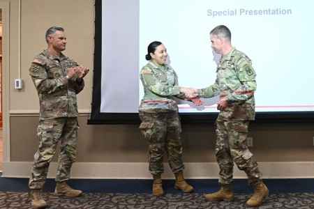 Pfc. Amanda Sanchez,  center,  is awarded a commanding general’s coin by Joint Readiness Training Center and Fort Johnson commanding general Brig. Gen. Jason A. Curl, right, and Command Sgt. Maj. Oracio Peña, left, her life-saving efforts of...