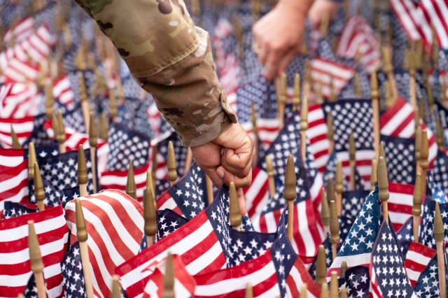 Service members, families and community members come together to honor the memory of Sept. 11, 2001, by placing flags at the Rock Island Arsenal 9/11 memorial. Each flag is carefully positioned in the ground behind the brick replica of the World...