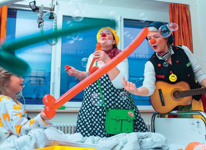 Singen, Quatschmachen und Schabernack treiben: Klinikclowns sind für kleine Patientinnen und Patienten oft eine willkommene Abwechslung zum oft eher ernsten Klinikalltag. Foto: picture alliance/Jens Büttner