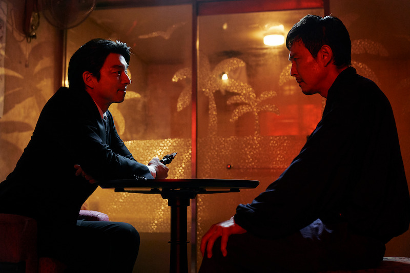 Lee Jung-jae as Seong Gi-hun sits across the table from a man in 'Squid Game' Season 2 