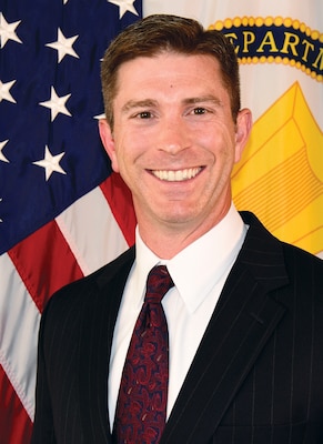 Man in suit and tie in front of US flag.