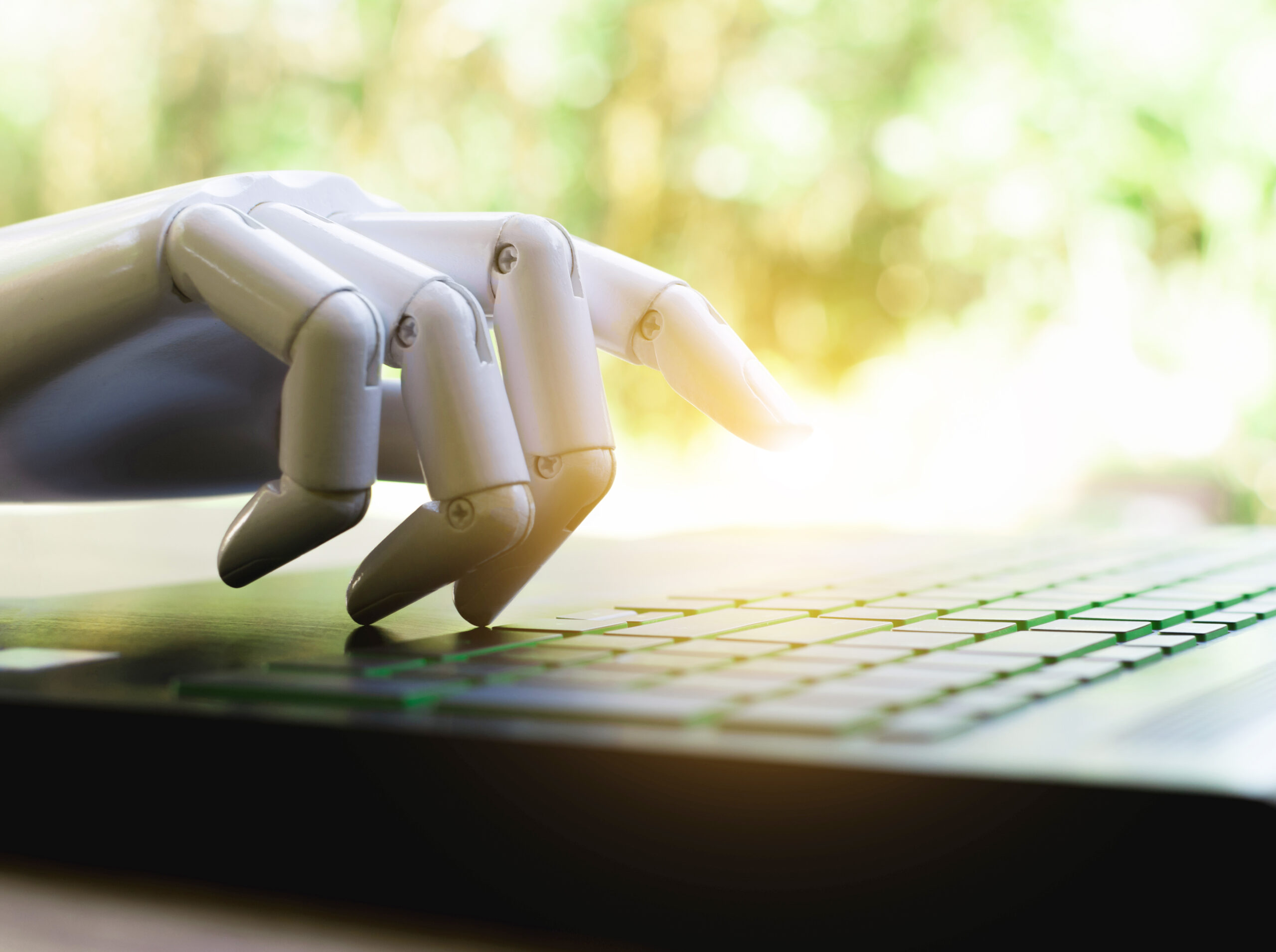 A robotic hand types on a computer keyboard, signifying the advances in AI technology's ability to be creative and craft stories.