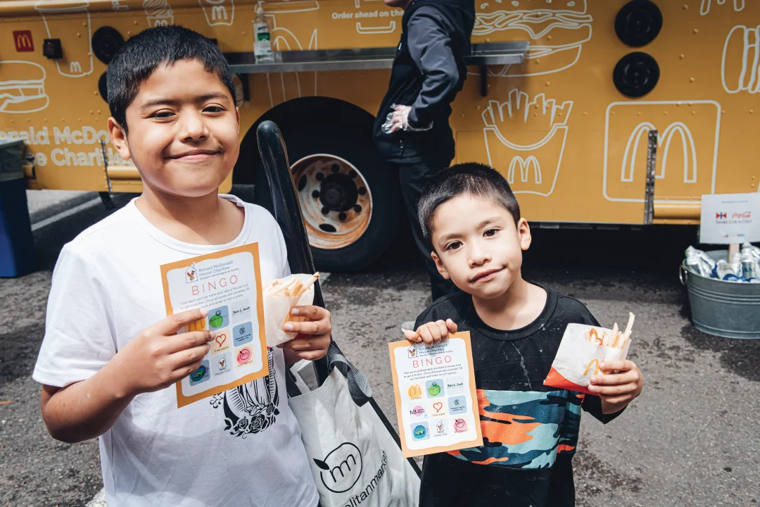 two young siblings smiling with gifts and food from RMHC Seattle open house