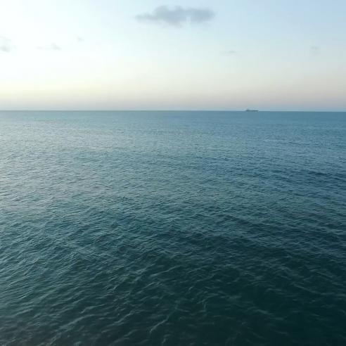 View of the ocean surface with a ship on the horizon