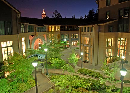 Winding walkway with landscaping through courtyard of building illuminated by lights at night