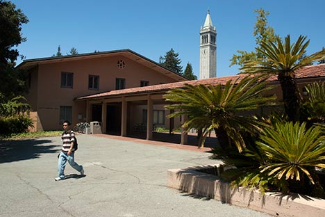 Terra cotta colored building with breezeway and person walking in front