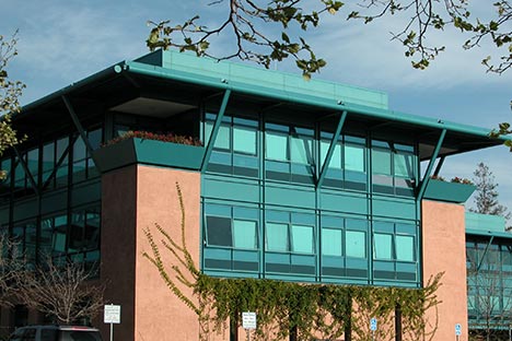 Light terra cotta stucco building with turquoise colored glass windows and roof