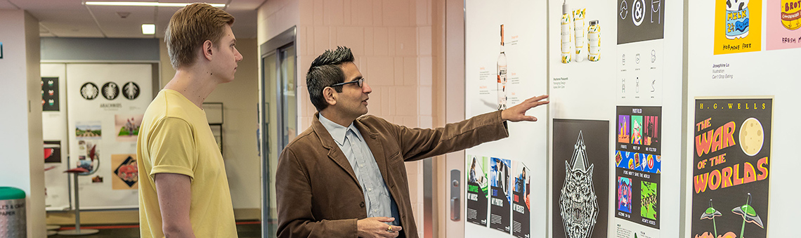 Student with teacher looking at artwork in hallway