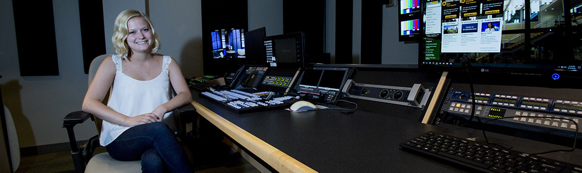 student sitting at a control board