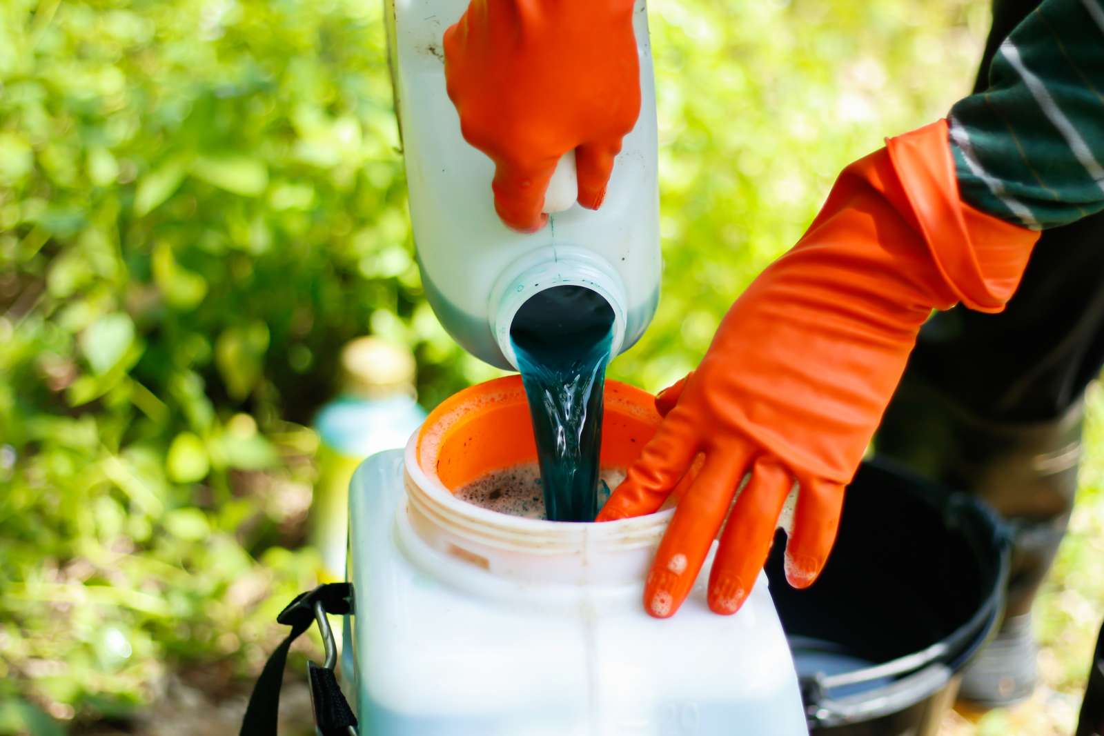 Agricultural worker pours pesticide into a container for application