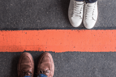 Two people stand either side of a red line, symbolizing setting boundaries in relationships.