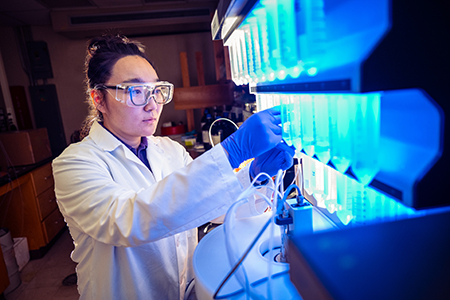 Wei Wu works with several tubes filled with blue liquid.