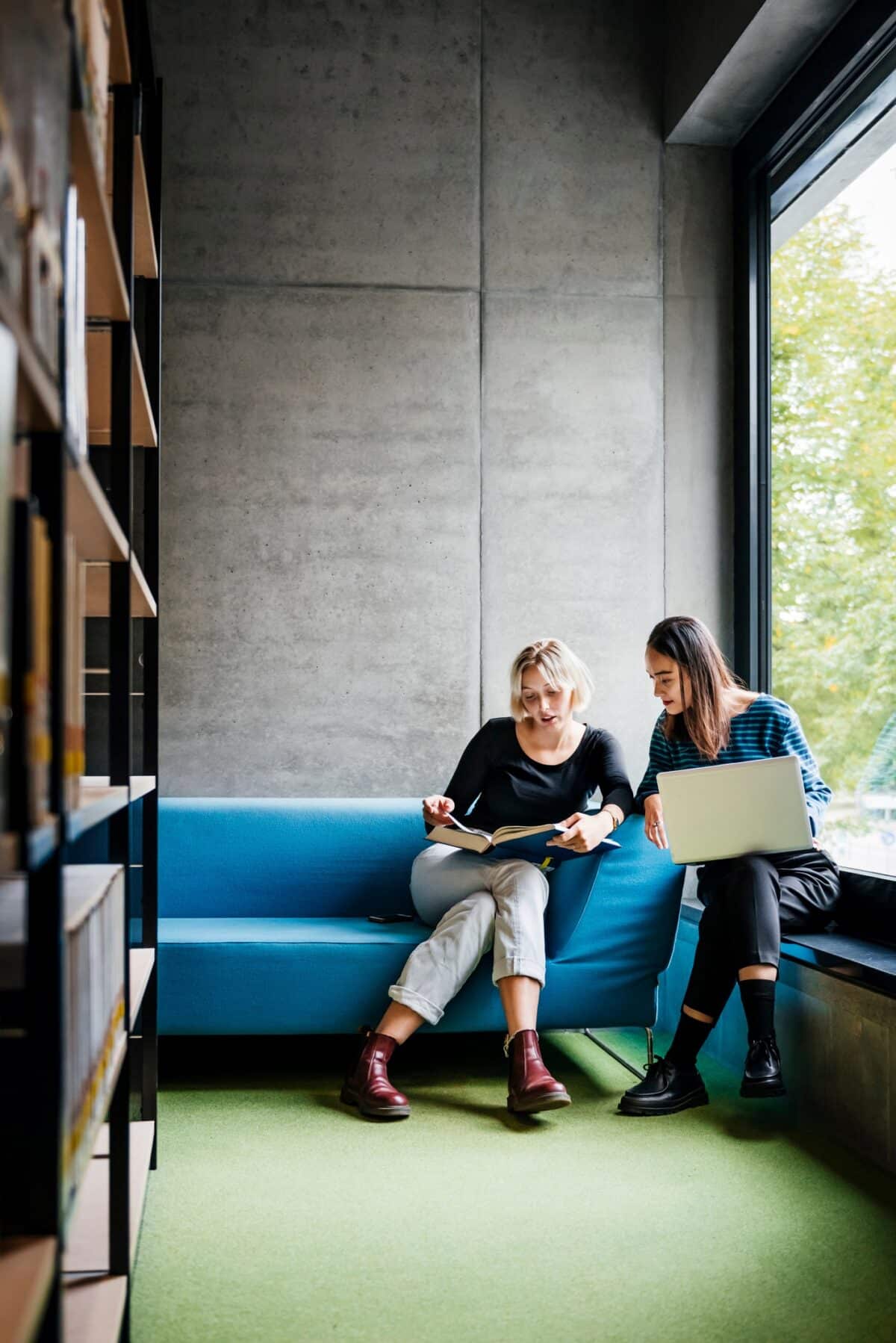 Two friends working together in quiet library space.