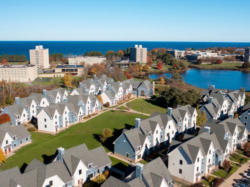 Aerial view of campus with The Village in the foreground, Glimmerglass Lagoon and a background of lakeside buildings and Lake Ontario