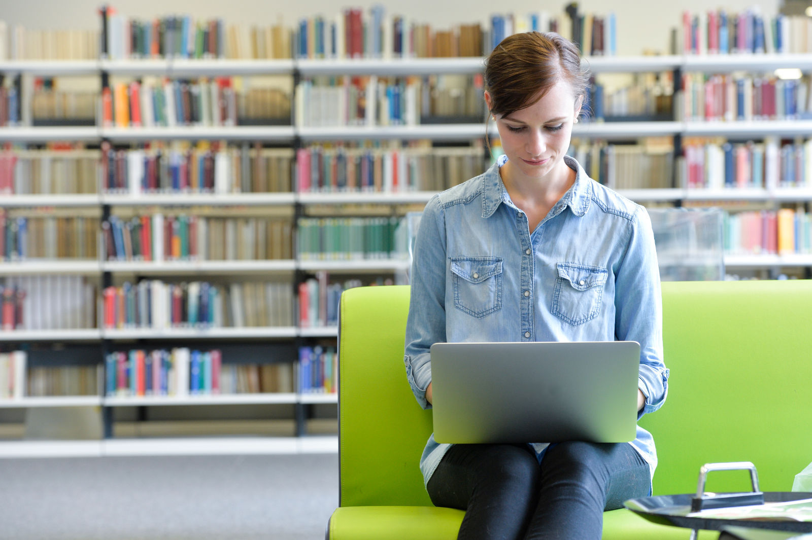 Foto einer Person am Laptop in der Bibliothek